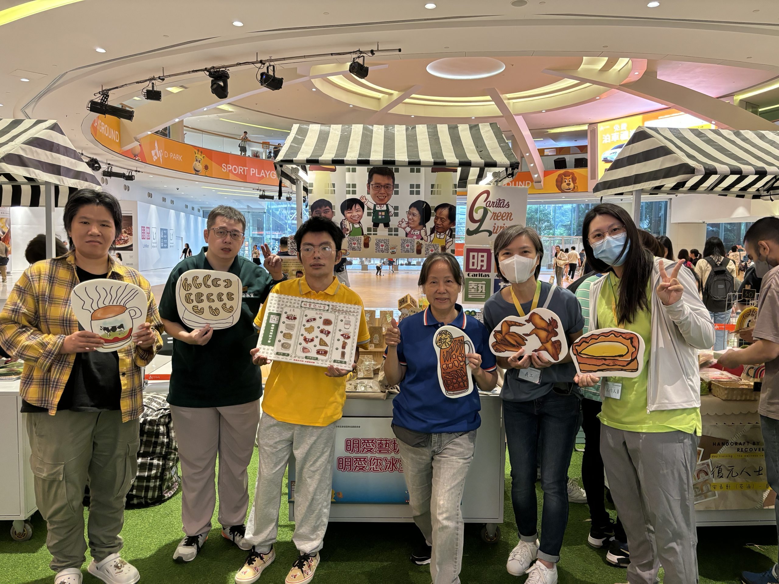老闆阿滿、老闆健仔、義工及職員手持由滿老闆印的茶餐廳食物打氣牌來一幅合照。
