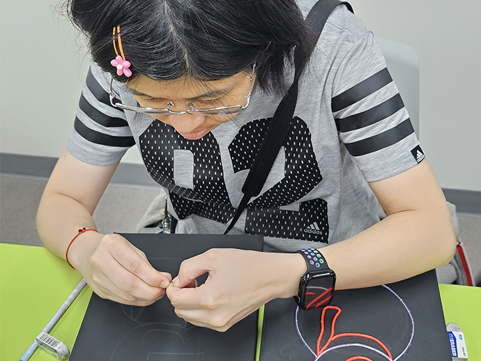 組員正在專心致志地用不用顏色的冷光線勾製作品。