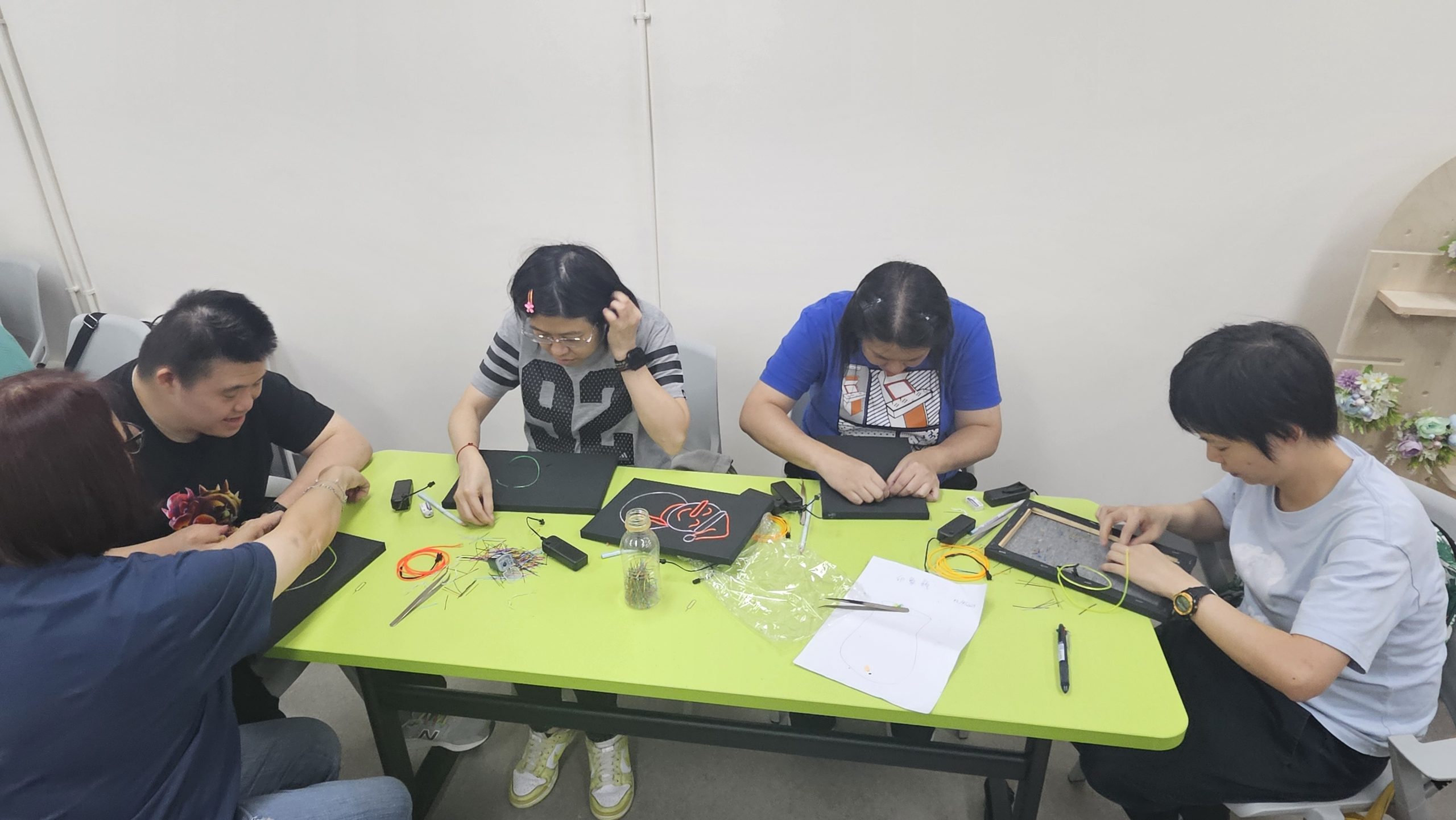 組員在桌子上專注製作冷光線（霓虹燈）作品。