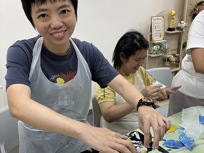 組員穿著圍裙，專注地用葉子托印葉脈並印在椅子上。