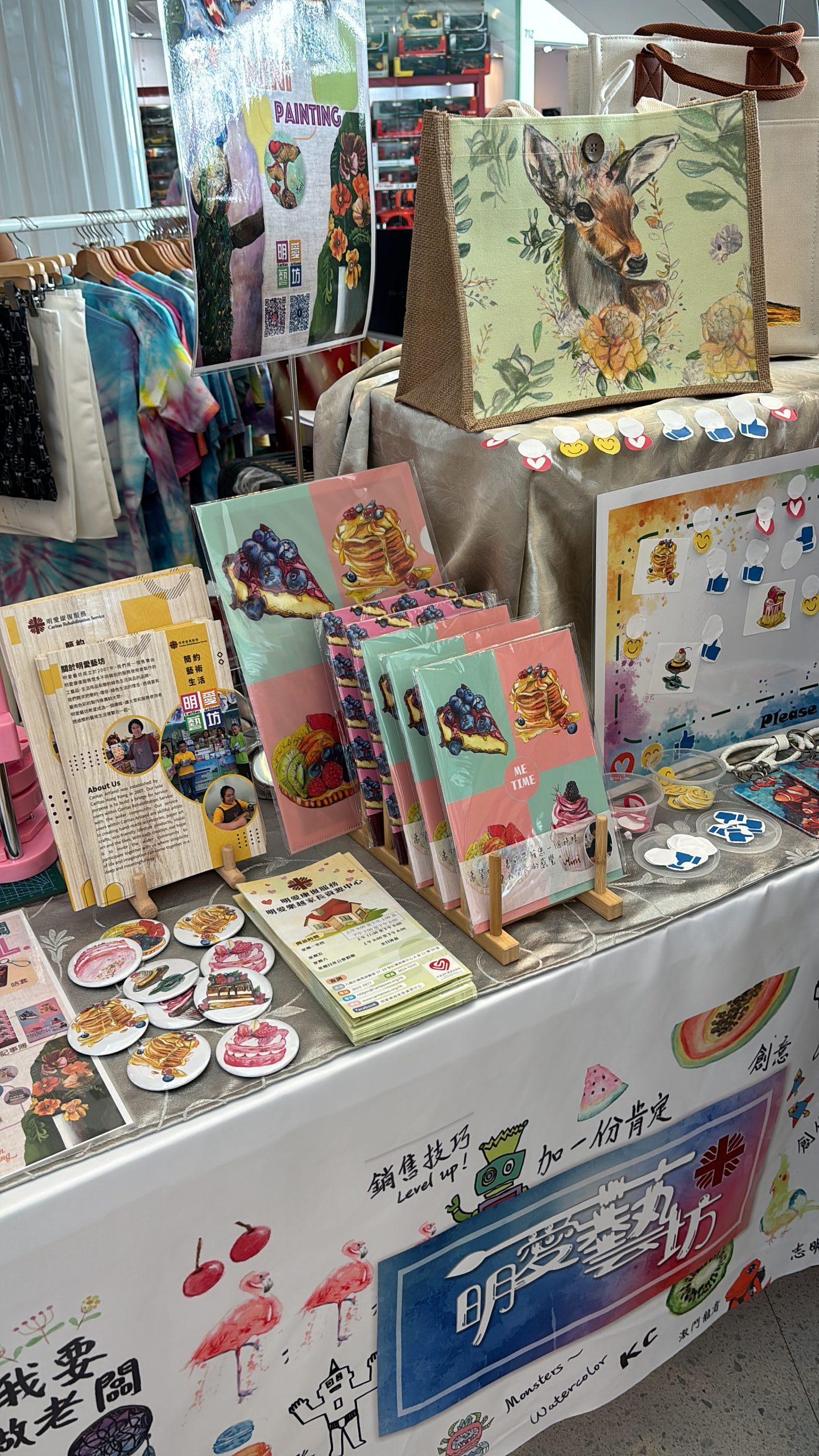 一張桌子上擺滿了老闆Mini各式各樣的手工藝產品，如種子書籤、甜品文件閘、甜品襟章等。